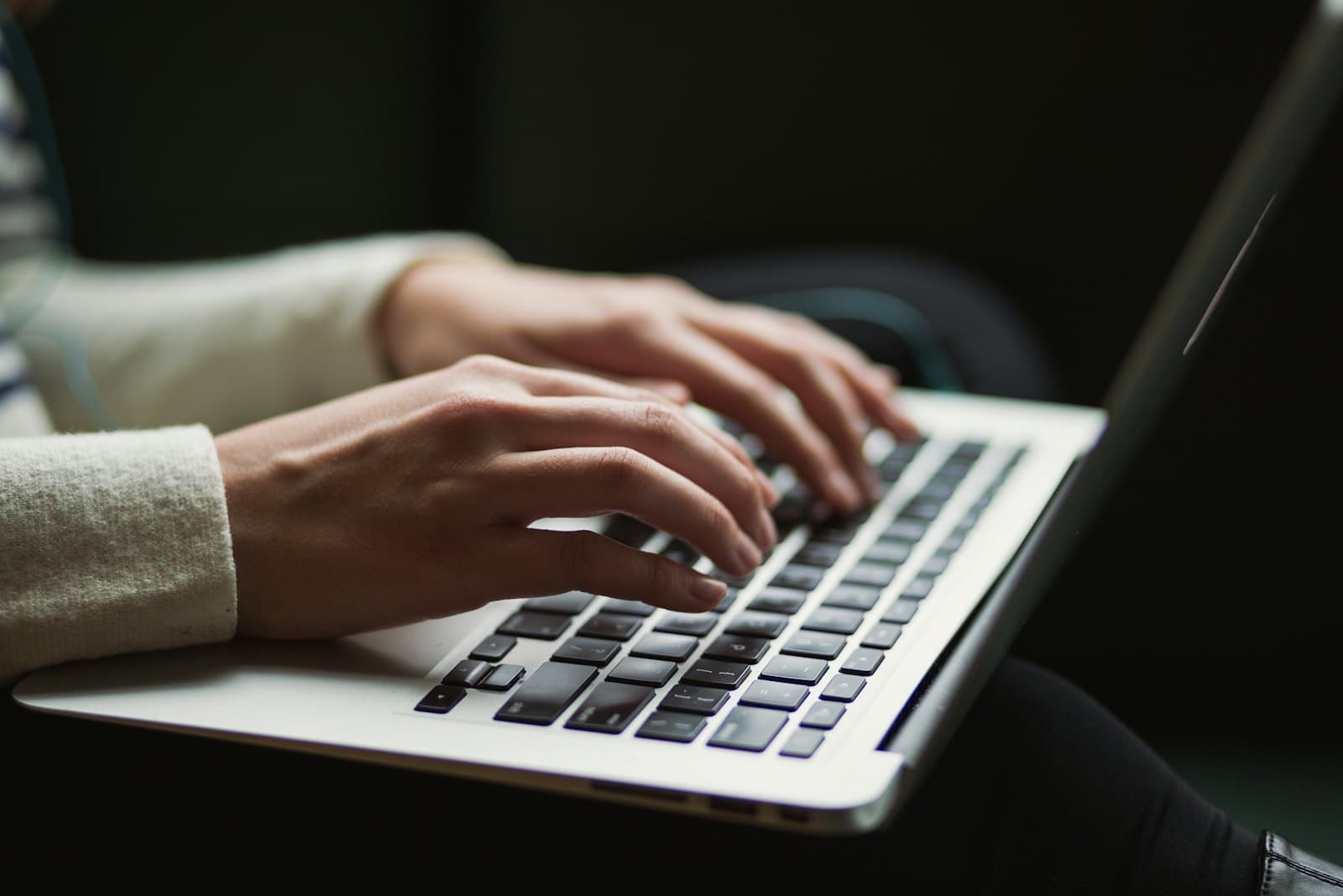 Close-up of hands typing on a laptop keyboard, the screen out of view.