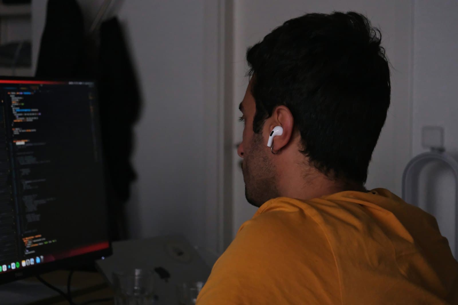 Someone working at a desk in front of monitors showing code, seen from behind.