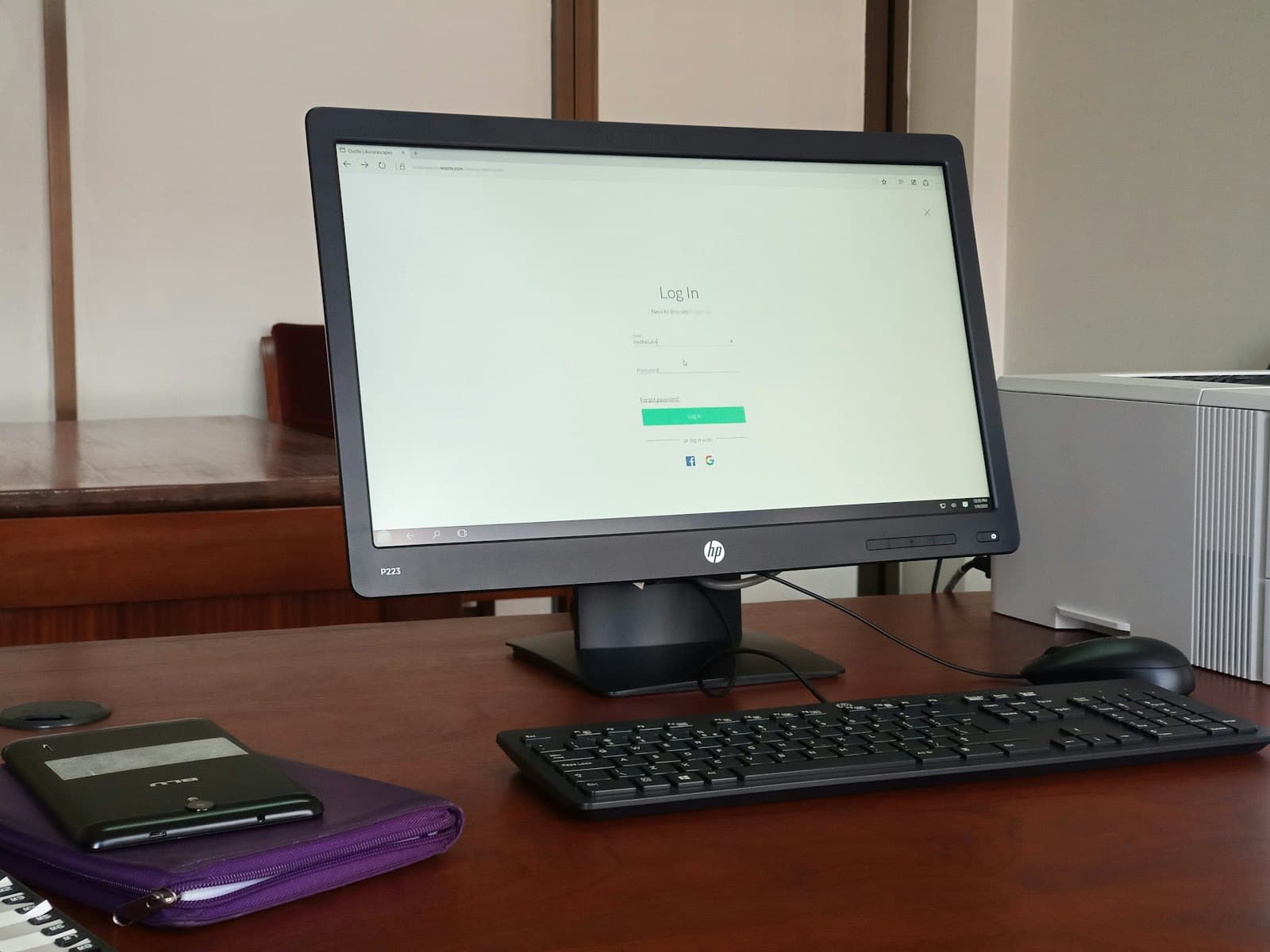 An older desktop monitor and keyboard on a wooden desk.