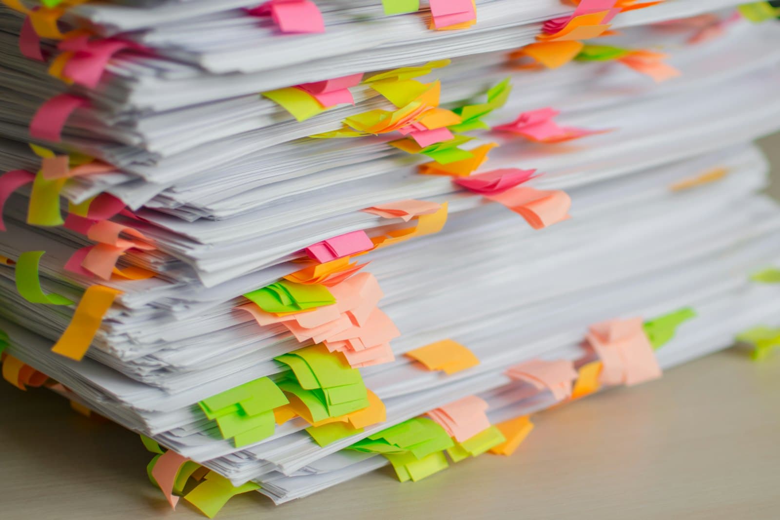 A tall stack of printed documents bristling with colored sticky-note tabs.