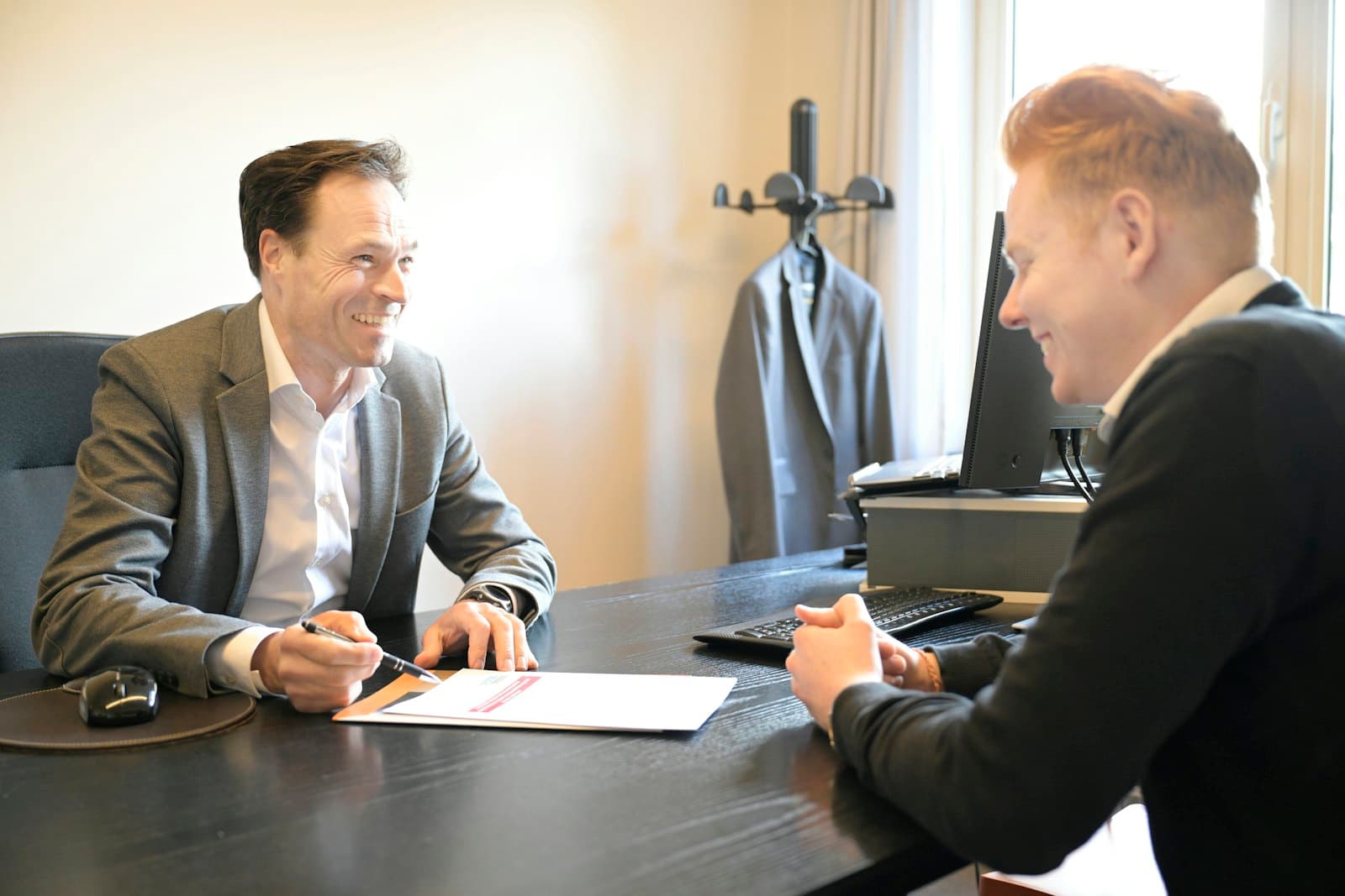 Two people going through paperwork together across an office desk.