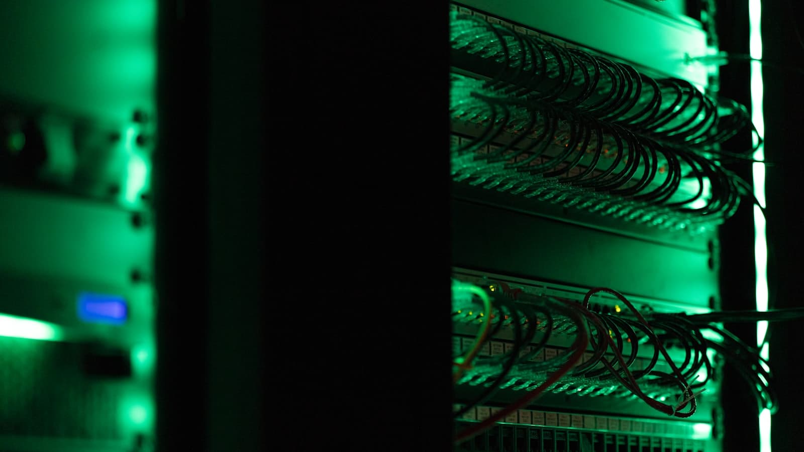 A server rack in a dark room, its status lights glowing green.