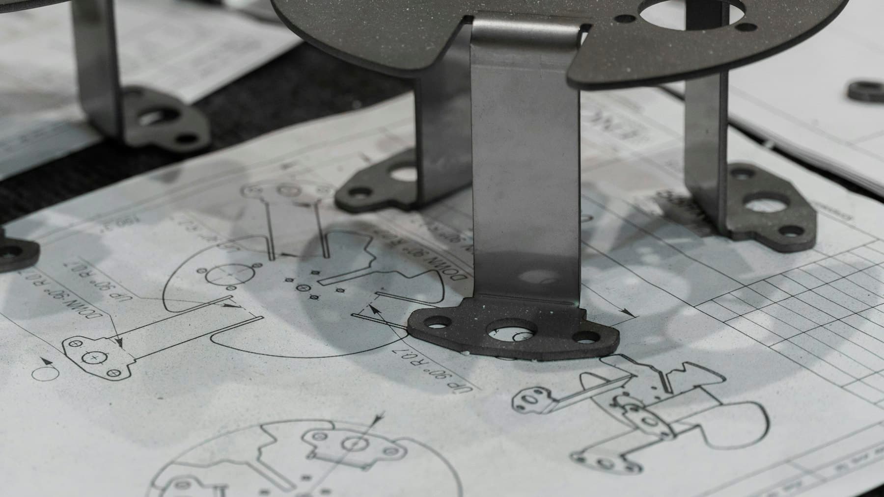 Machined metal components resting on a technical drawing.