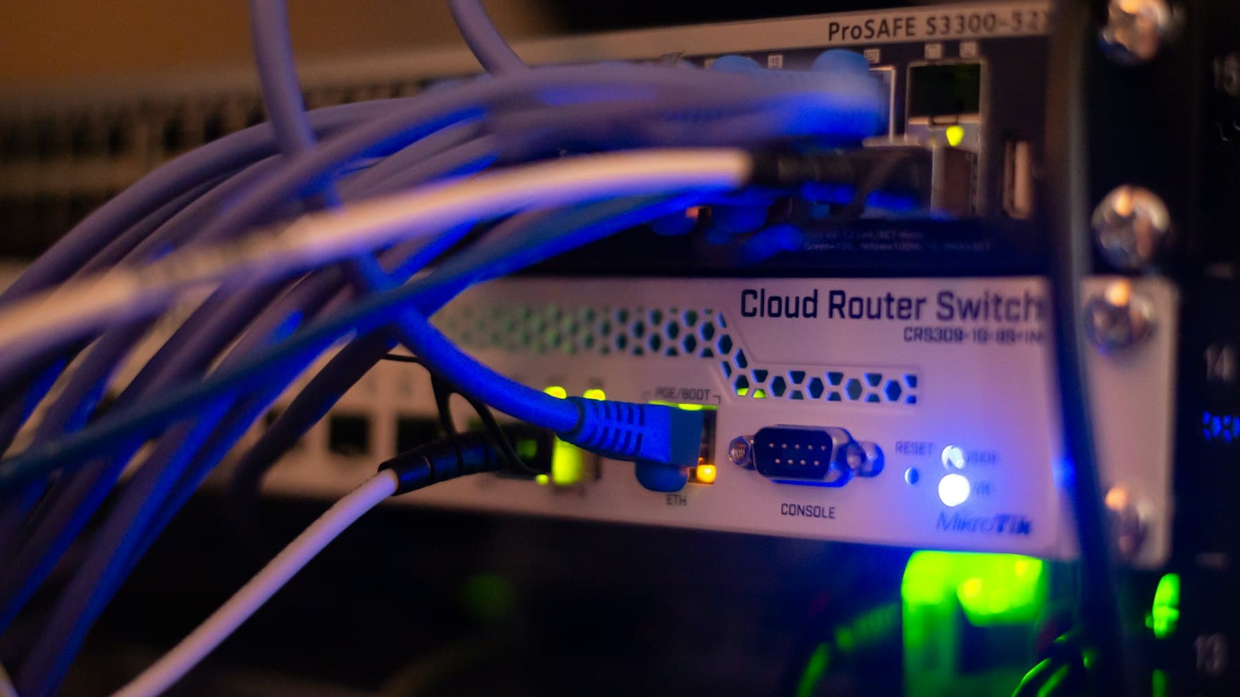 Network cables patched into a rack-mounted router and switch, status lights lit.